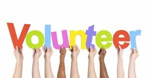 Hands hold up volunteer sign